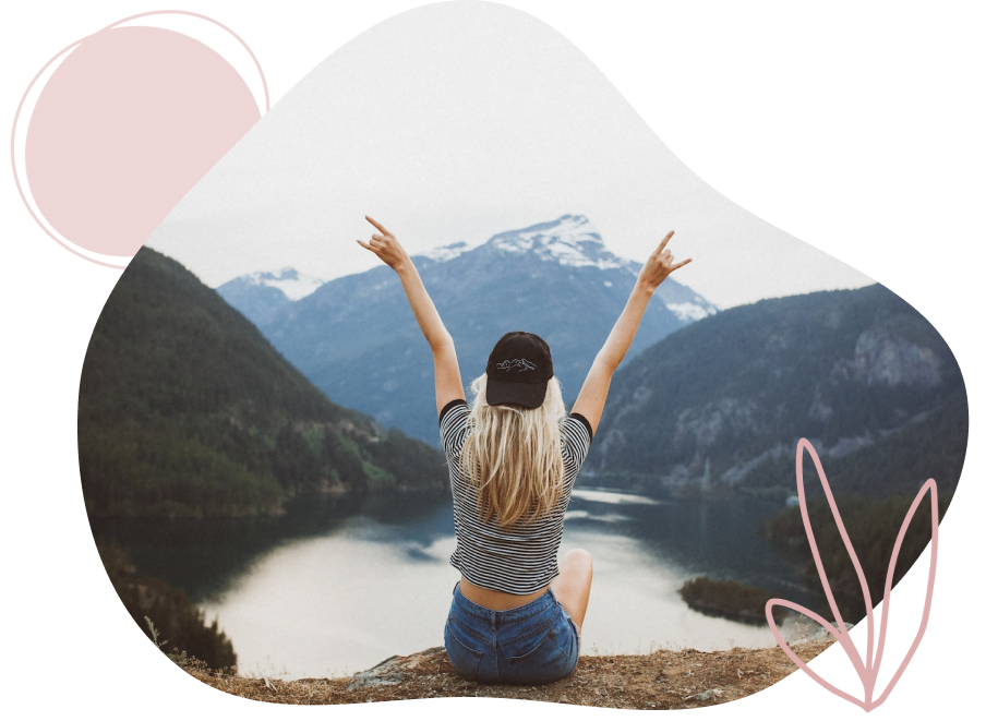 אישה יושבת על קצה הר עם ידיים מורמות למעלה